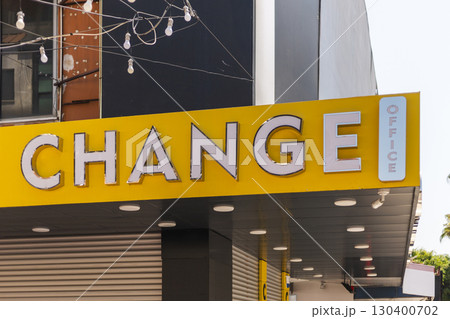 The bright yellow sign displays the word CHANGE prominently above the entrance of a currency exchange office. The location is bustling and vibrant, hinting at commerce and travel The bright yellow sign displays the word CHANGE prominently above the entrance of a currency exchange office. The location is bustling and vibrant, hinting at commerce and travel 130400702
