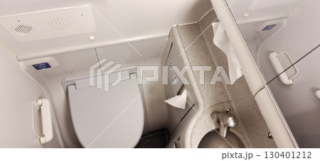 The setting features a clean restroom with a toilet and a small sink, designed for convenience on a train. The space is efficiently utilized, showcasing modern amenities for travelers 130401212