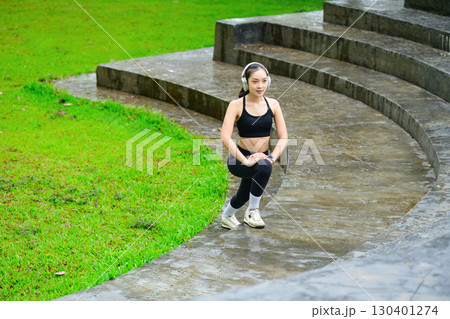 Female athlete in black sportswear warming up before workout, exercising with determination 130401274