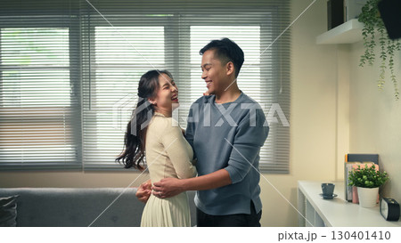 Romantic portrait of cheerful couple embracing indoors, sharing laughter and affection together Romantic portrait of cheerful couple embracing indoors, sharing laughter and affection together 130401410