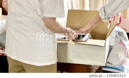 断捨離中にダンボール箱を開けて見る2人の手元 130402423
