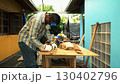 Carpenter measuring wooden plank on workbench with ruler while wearing safety mask and gloves 130402796