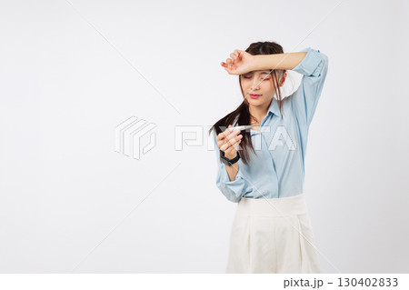 Asian sick woman, feverish with hand on forehead, checks temperature, feeling sick, reading thermometer to measure illness and seeking medical care for her health, isolated studio white background 130402833