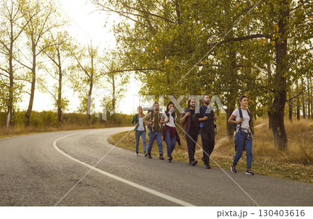 Hiking Team of Friends Walking Together on a Scenic Road Hiking Team of Friends Walking Together on a Scenic Road 130403616