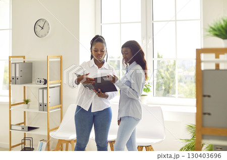 Young business women having meeting at office standing with financial documents and talking. Young business women having meeting at office standing with financial documents and talking. 130403696
