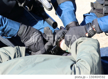 警察による銃器犯罪対処訓練の情景：犯人の手にかけられた手錠部分のアップ 130404592