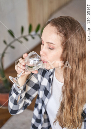 Young caucasian woman enjoying a glass of water at home Young caucasian woman enjoying a glass of water at home 130405167