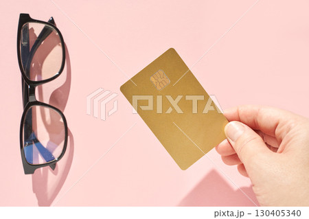 Caucasian adult hand holding gold credit card on pink background near Caucasian adult hand holding gold credit card on pink background near 130405340