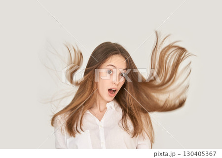 Surprised caucasian young female with long brown hair in motion against white Surprised caucasian young female with long brown hair in motion against white 130405367