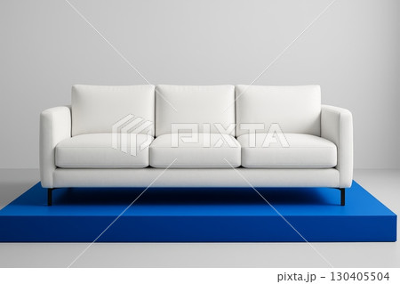 White modern sofa on blue platform against light grey wall in minimal interior, contemporary furniture front view 130405504