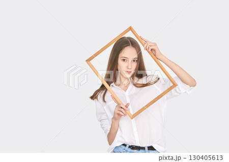 Young caucasian female posing with wooden frame, long hair, white shirt, casual 130405613