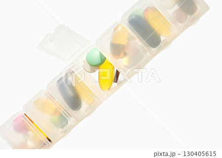 Daily pill organizer with various colorful tablets and supplements for health 130405615