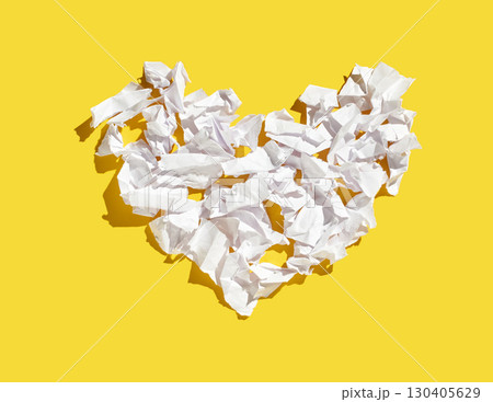 Crumpled white paper sheets shaped into heart on vibrant yellow background Crumpled white paper sheets shaped into heart on vibrant yellow background 130405629