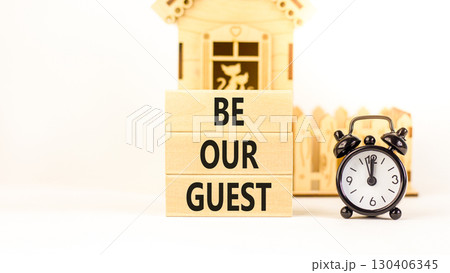 Be our guest symbol. Concept words Be our guest on beautiful wooden block. Black alarm clock. Beautiful white background. Business and be our guest concept. Copy space. 130406345