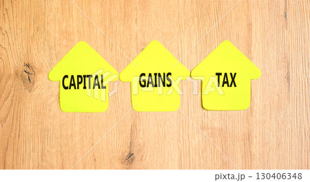 Capital gains tax symbol. Concept words Capital gains tax on beautiful yellow paper houses. Beautiful wooden background. Business and capital gains tax concept. Copy space. 130406348