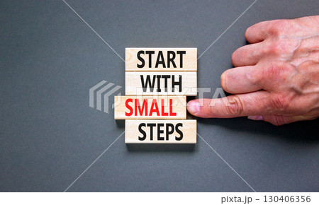 Start with small steps symbol. Concept words phrase Start with small steps on beautiful wooden blocks. Beautiful grey background. Businessman hand. Business Start with small steps concept. Copy space. Start with small steps symbol. Concept words phrase Start with small steps on beautiful wooden blocks. Beautiful grey background. Businessman hand. Business Start with small steps concept. Copy space. 130406356