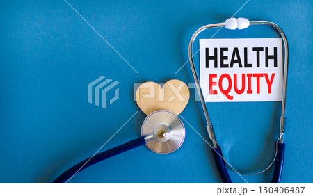 Health equity symbol. Concept words Health equity on beautiful white card. Wooden heart and stethoscope. Beautiful blue background. Medical healthy lifestyle health equity concept. 130406487