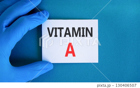 Vitamin A symbol. Concept words Vitamin A on beautiful white card. Doctor's hand in blue medical glove. Beautiful blue background. Medical healthy lifestyle Vitamin A concept. Vitamin A symbol. Concept words Vitamin A on beautiful white card. Doctor's hand in blue medical glove. Beautiful blue background. Medical healthy lifestyle Vitamin A concept. 130406507