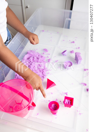 Child playing with purple kinetic sand and pink toy tools Child playing with purple kinetic sand and pink toy tools 130407277