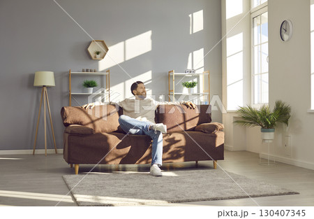 Happy man enjoying free time and relaxing on a comfortable sofa in the living room 130407345