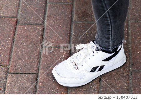 Stylish White Sneakers Lying on a Brick Pavement Surface Stylish White Sneakers Lying on a Brick Pavement Surface 130407613