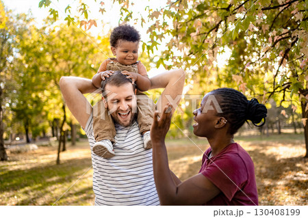 Joyful family moment in a sunlit park during autumn 130408199