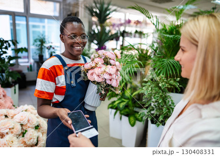 Florist holding flowers and accepting payment from customer using NFC technology 130408331