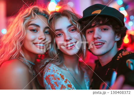 A diverse group of young friends smiling cheerfully at a vibrant night club party with colorful blurred bokeh lights in the background. 130408372
