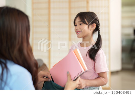 Child smiling while receiving school supplies from parent Child smiling while receiving school supplies from parent 130408495