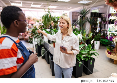 Florist showing plants to customer in a flower shop Florist showing plants to customer in a flower shop 130408733