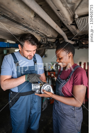 Mechanics examining turbocharger in auto repair shop 130408755
