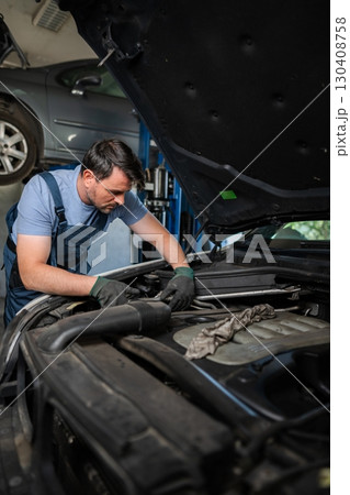 Mechanic repairing car engine in auto repair shop 130408758