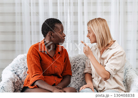 Two female friends arguing while sitting on a sofa at home 130408838