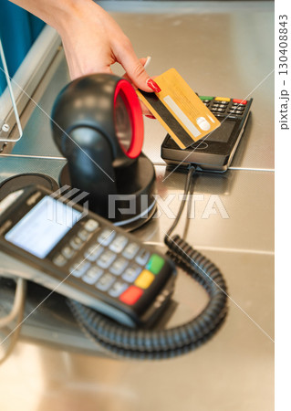 Cashier making contactless payment with credit card at supermarket checkout Cashier making contactless payment with credit card at supermarket checkout 130408843