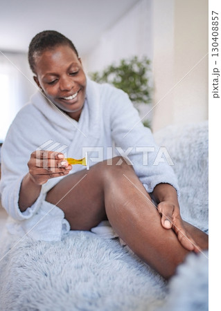 Young woman shaving legs with razor at home Young woman shaving legs with razor at home 130408857