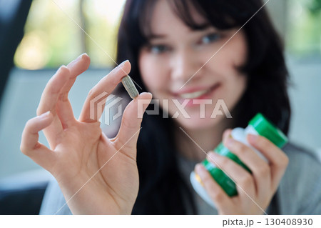 Close up of herbal phyto capsule and bottle in hands of young smiling woman 130408930