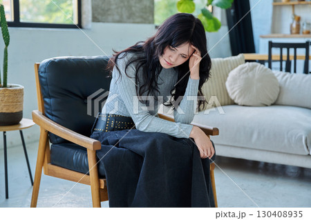 Unhappy upset tired young woman sitting on chair at home Unhappy upset tired young woman sitting on chair at home 130408935