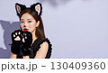 ハロウィンの猫コスプレの若い女性が笑顔でポーズを決める 130409360