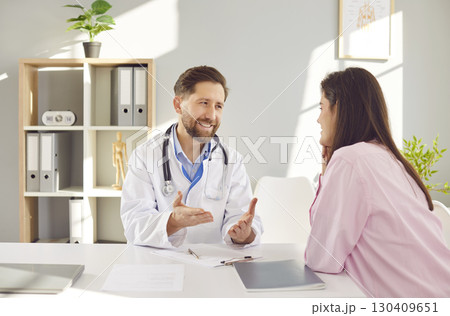 Caring male doctor in white medical uniform talking to discuss results or symptoms with patient Caring male doctor in white medical uniform talking to discuss results or symptoms with patient 130409651