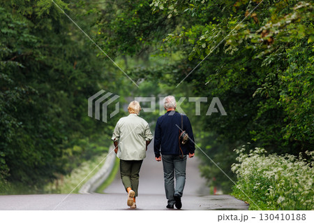 Couple walking hand in hand along a peaceful forest path during a warm summer afternoon Couple walking hand in hand along a peaceful forest path during a warm summer afternoon 130410188