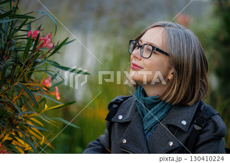 Woman enjoying nature while admiring flowers in a lush garden during the spring season 130410224