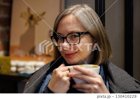 Woman enjoying a warm beverage in a cozy cafe during a relaxed afternoon Woman enjoying a warm beverage in a cozy cafe during a relaxed afternoon 130410229