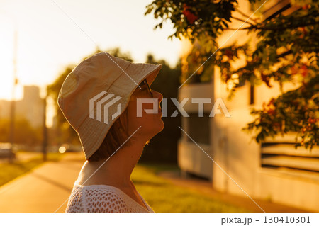 Person enjoying golden hour light while admiring a tree in an urban setting Person enjoying golden hour light while admiring a tree in an urban setting 130410301