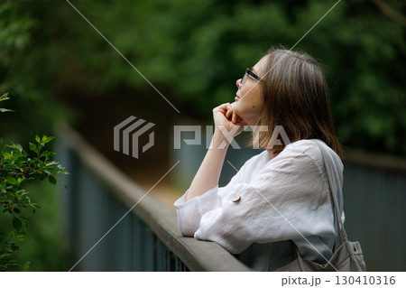 Contemplative woman gazes thoughtfully into nature on a peaceful afternoon in the park Contemplative woman gazes thoughtfully into nature on a peaceful afternoon in the park 130410316