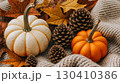 Ripe orange pumpkins with autumn decor next to a cozy checkered blanket on a wooden background 130410386