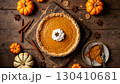 Pumpkin pie on a wooden table, cinnamon sticks and small decorative pumpkins placed around 130410681