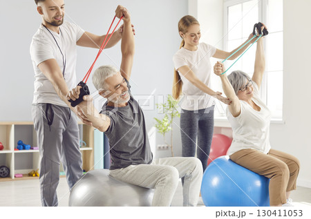 Doctor And Trainer Leading Elderly Couple In Rehabilitation Session Doctor And Trainer Leading Elderly Couple In Rehabilitation Session 130411053