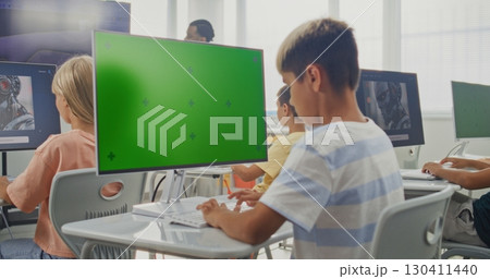 Elementary School Boy Using Computer with Green Screen Mockup During Digital Art Lesson 130411440