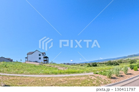 A residential neighborhood on a gentle hillside in Castle Rock, Colorado with green grass and homes visible in the background. The photo is taken under bright daylight with a wide perspective. A residential neighborhood on a gentle hillside in Castle Rock, Colorado with green grass and homes visible in the background. The photo is taken under bright daylight with a wide perspective. 130411797