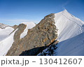 The sharp, steep ridge of Piz Palu rises prominently against the blue sky. Hikers traverse this rugged terrain, surrounded by snow and glaciers in the stunning Swiss Alps. 130412607